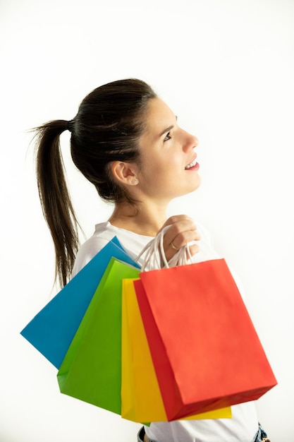 Frau im Profil, die bunte Taschen auf einem weißen Hintergrund hält Einkaufskonzept Verkäufe Schwarzer Freitag Weihnachten
