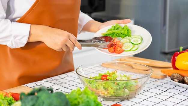 Frau im Prozess der Zubereitung von gesundem Essen Gemüsesalat, der Salat mischt