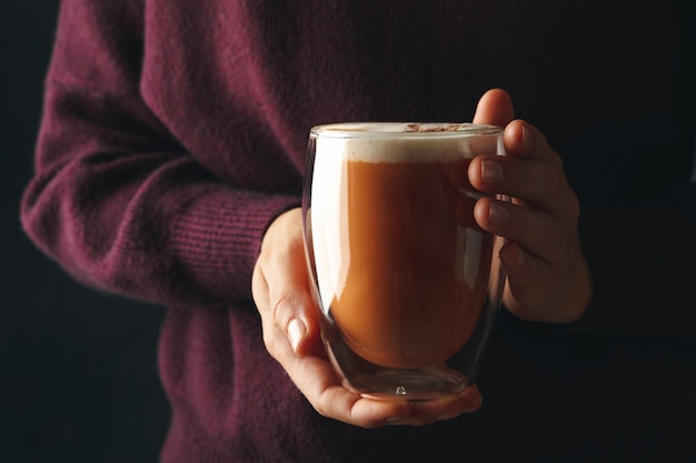 Frau im Pullover hält ein Glas Kürbis Latte