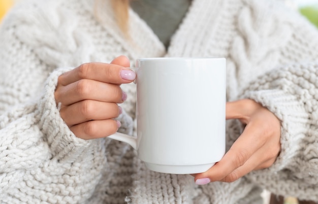 Frau im Pullover hält eine Tasse Kaffee