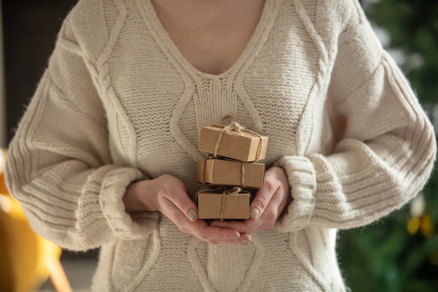 Frau im Pullover hält Geschenkbox zu Hause