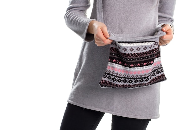 Frau im Pullover hält Tasche. Handtasche mit dunklem Aufdruck. Langer warmer Pullover. Graues Wollkleid und Geldbörse.