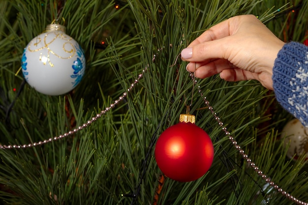 Frau im Pullover Weihnachtsbaum mit Spielzeugbällen schmücken