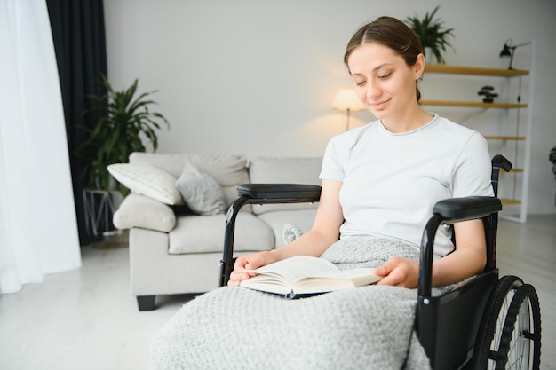 Frau im Rollstuhl liest zu Hause Buch