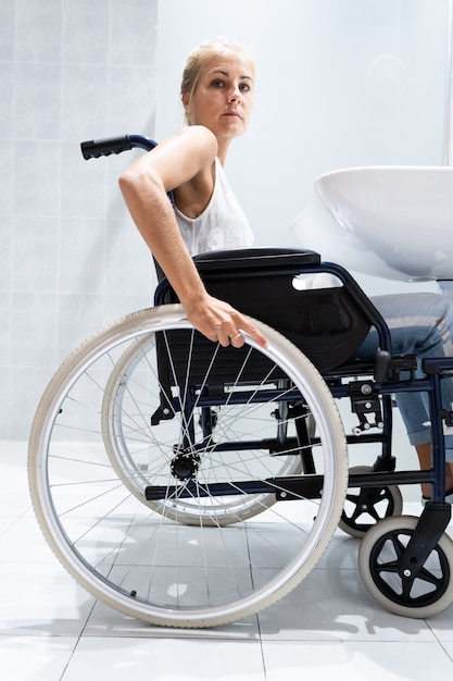 Frau im Rollstuhl mit den Händen am Lenkrad