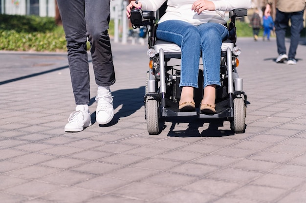 Frau im Rollstuhl mit einem Mann beim Spazierengehen