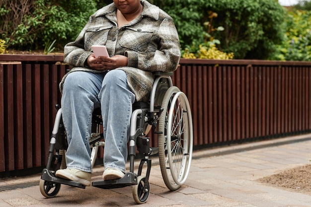 Frau im Rollstuhl mit Telefon im Freien