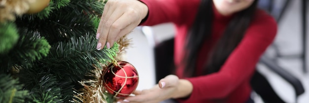 Frau im Rollstuhl schmückt Weihnachtsbaum mit roter Kugel