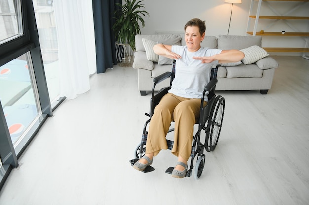 Frau im Rollstuhl trainiert im Wohnzimmer