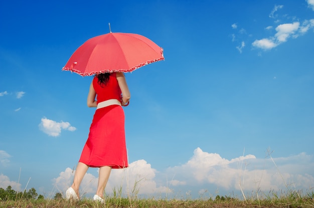 Frau im Rot mit Regenschirm und blauem Himmel