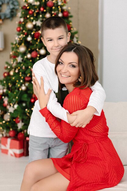 Frau im roten Kleid. Mutter und Sohn im Weihnachtsdekorationshaus. Familienportrait Weihnachtsstimmung