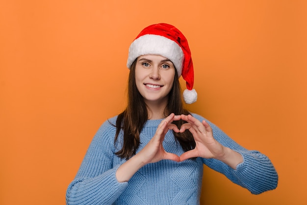 Frau im roten Weihnachtshut, macht Herzgeste