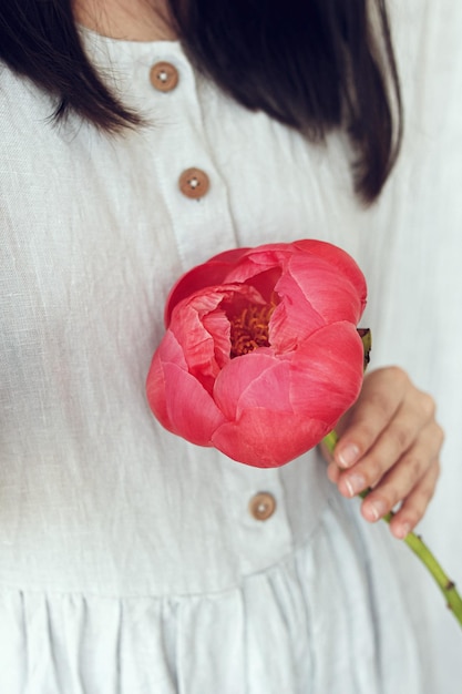 Frau im rustikalen Kleid mit schöner Pfingstrose Stilvolle große rosa Pfingstrose in der Hand aus nächster Nähe