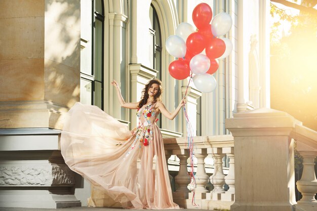 Frau im schönen Kleid mit vielen bunten Luftballons