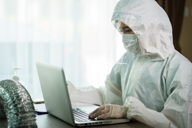 Frau im Schutz Hazmat Anzug Arbeiter im Labor Computer Analyse im Labor. um die Verbreitung von Coronavirus oder COVID-19 zu stoppen.