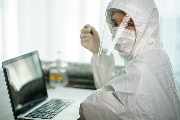 Frau im Schutz Hazmat Anzug Arbeiter im Labor Computer Analyse im Labor. um die Verbreitung von Coronavirus oder COVID-19 zu stoppen.