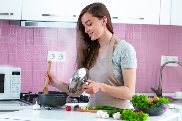 Frau im Schutzblech Abendessen vom frischen reifen Gemüse in der Küche zu Hause kochend