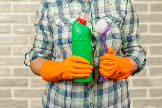 Frau im Schutzhandschuh mit Flasche Waschmittel