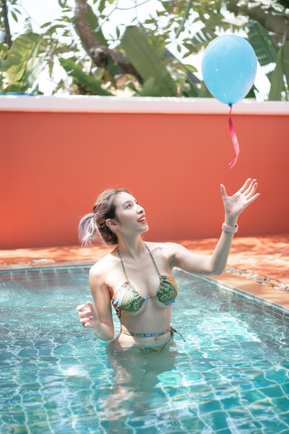 Frau im Schwimmbad, die Spaß mit Luftballons hat.