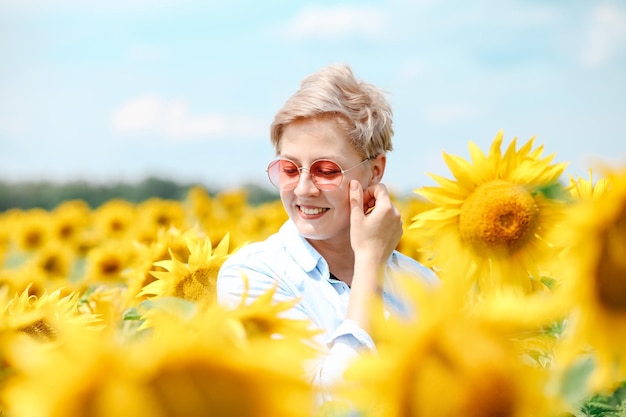 Frau im Sonnenblumenfeld Sommer Junge schöne Frau, die im Sonnenblumenfeld steht