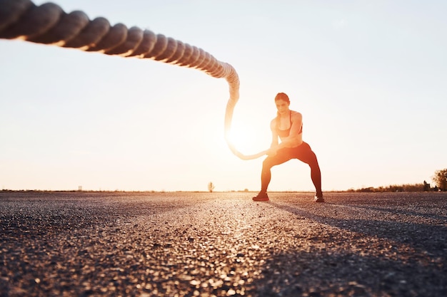 Foto frau im sportbekleidungstraining mit knoten auf der straße zur abendzeit