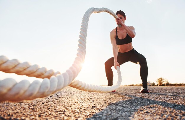 Frau im Sportbekleidungstraining mit Knoten auf der Straße zur Abendzeit