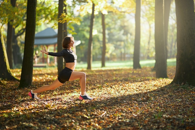 Frau im sportoutfit beim aufwärmen im park vor dem joggen