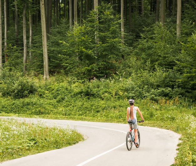 Frau im Sturzhelmreiten auf Gebirgsfahrrad.