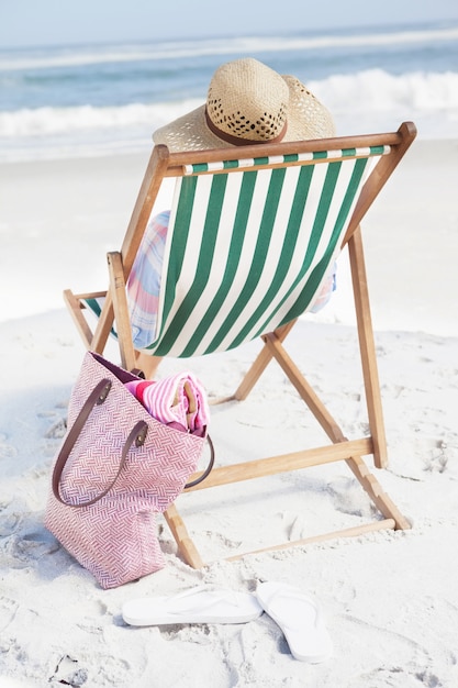 Frau im Sunhat, der auf Strand im Klappstuhl sitzt