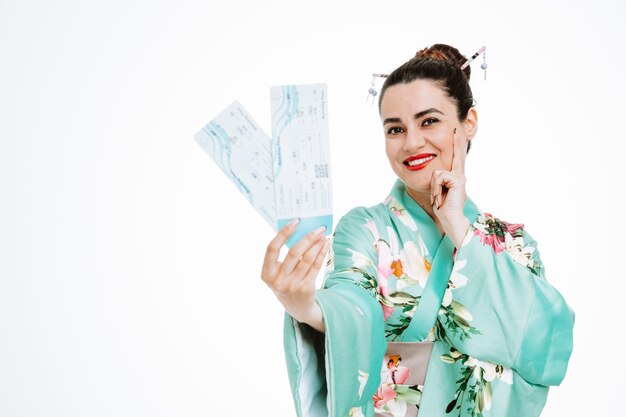 Frau im traditionellen japanischen Kimono, die Flugtickets glücklich und erfreut auf Weiß hält