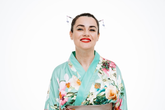 Foto frau im traditionellen japanischen kimono glücklich und positiv lächelnd zuversichtlich auf weiß