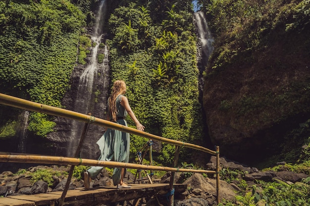 Frau im türkisfarbenen Kleid an den Sekumpul-Wasserfällen im Dschungel auf der Insel Bali Indonesien Bali Travel Concept