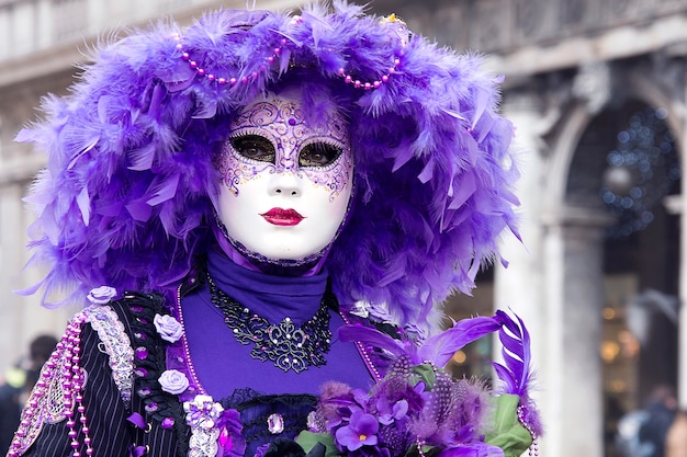 Frau im venezianischen Karnevalsoutfit in der Stadtstraße. Lila Farbe. Karneval. Traditioneller Karneval in Venedig