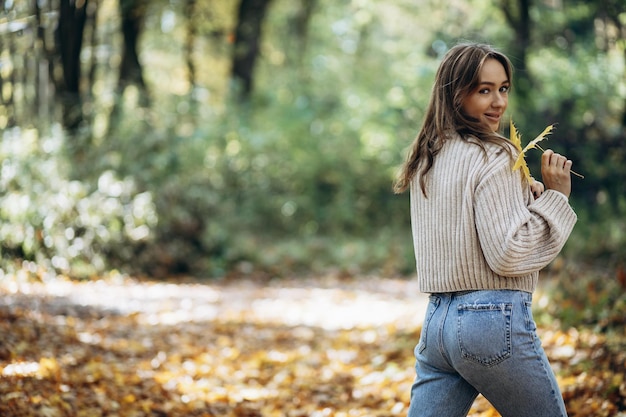 Frau im warmen Pullover, die im Herbstpark spaziert