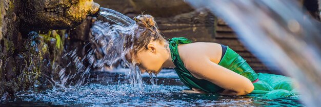 Frau im Wassertempel der heiligen Quelle in Bali. Das Tempelgelände besteht aus einer Petirtaan- oder Badestruktur, die für ihr heiliges Quellwasser BANNER im Langformat berühmt ist