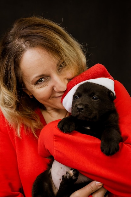 Foto frau im weihnachtsmannkostüm und welpe mit weihnachtsmütze