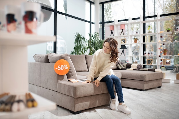 Foto frau im weißen hemd und in den jeans, die ein sofa untersuchen