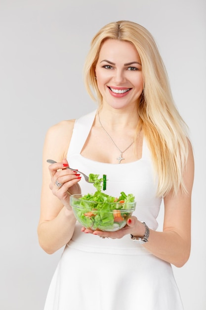 Frau im weißen Kleid mit frischem Salat