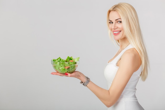 Frau im weißen Kleid mit frischem Salat