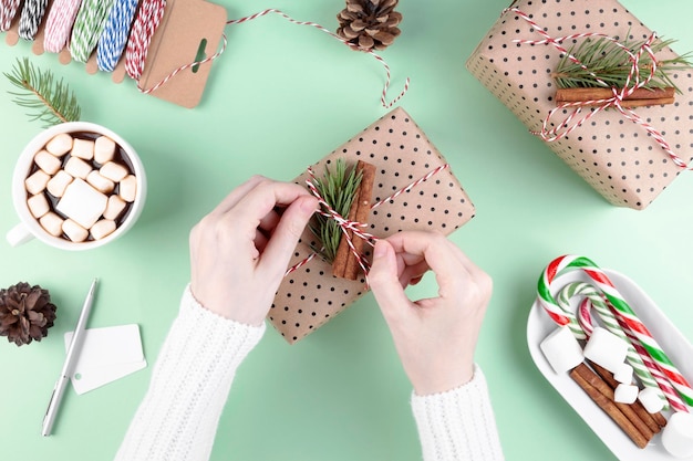 Frau im weißen Pullover packt Weihnachtsgeschenke aus Naturmaterialien für Geschenke