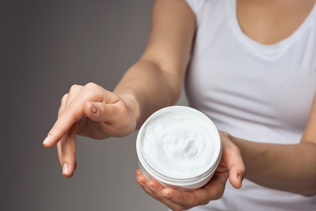 Frau im weißen T-Shirt hält Creme in den Händen Hautpflege feuchtigkeitsspendende Gesundheitshygiene