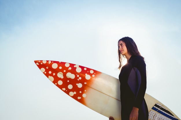 Frau im Wetsuit mit einem Surfbrett an einem sonnigen Tag