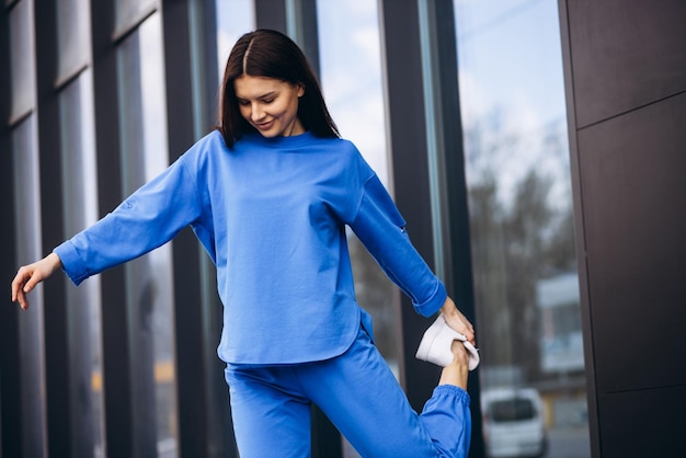 Frau in blauer Sportkleidung, die sich außerhalb der Straße erstreckt