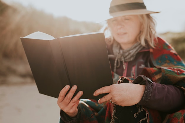 Frau in den 60ern, die im Freien ein Buch liest