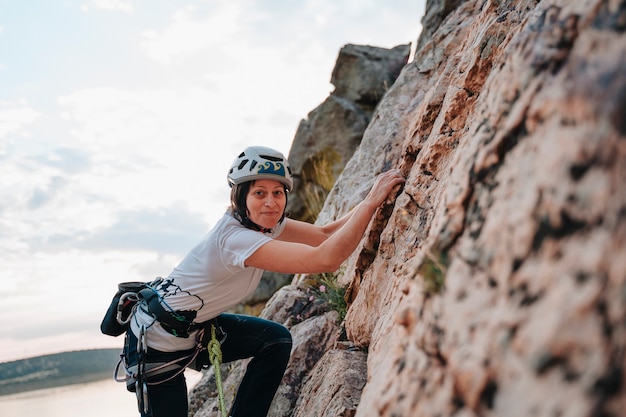 Frau in den Dreißigern, die einen Berg erklimmt, während sie in die Kamera schaut