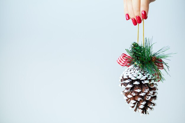 Frau in der Hand hält Weihnachtsschmuck auf hellem Hintergrund.