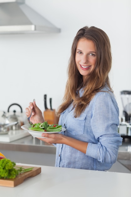 Frau in der Küche, die eine Salatschüssel hält