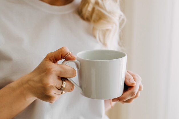 Frau in der Küche mit einer Tasse Kaffee am Morgen