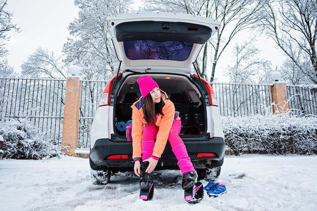 Frau in der Nähe des Autos, die sich auf das Wintertraining im Freien vorbereitet Winterfitnessübungen bei Kälte