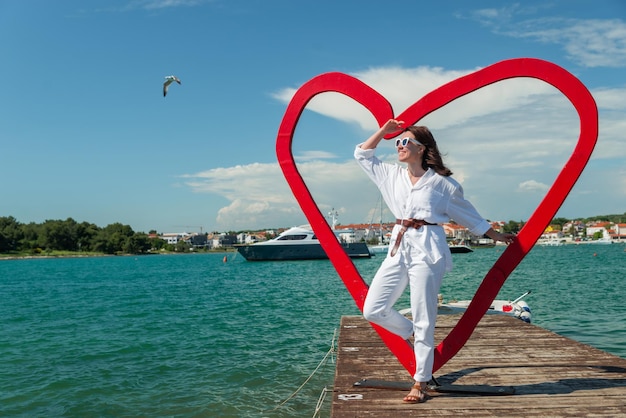 Frau in der Nähe von Herzform-Fotospot am Meeresstrand Kroatien Istrien